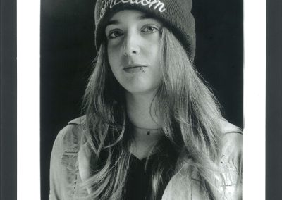 Ritratto di ragazza dai lunghi capelli biondi e occhi azzurri, indossante un cappello di lana con la scritta Freedom.