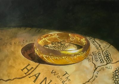 Grande primo piano dell'anello della saga di Tolkien, poggiato sulla mappa del Mondo di Mezzo