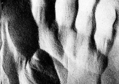 Foto in bianco e nero di segni lasciati sulla sabbia da una mano.